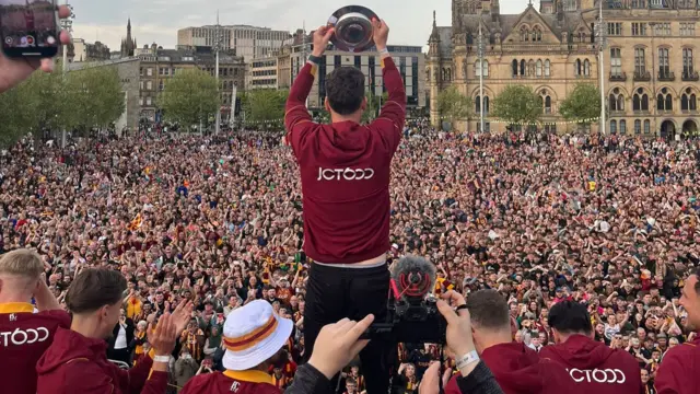 Captain Richie Smallwood holding up promotion shield in front of thousands of fans
