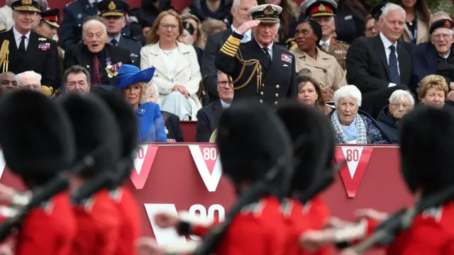 King Charles salutes as soldiers in bearskin hats and red uniforms march past at the parade