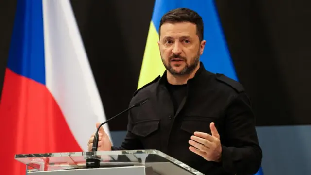 Zelensky stands in front of a Ukrainian and Czech flag