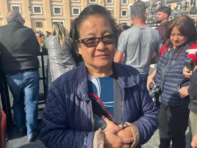 An older woman wearing a dark blue coat and glasses