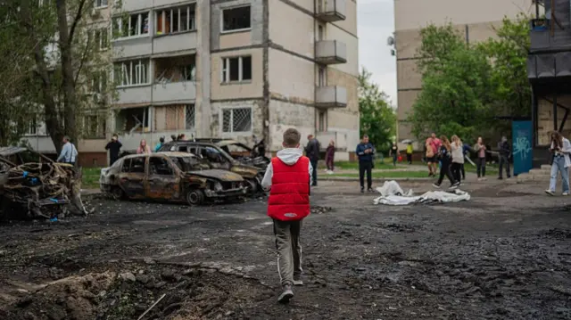 A boy walks through rubble in Kyiv