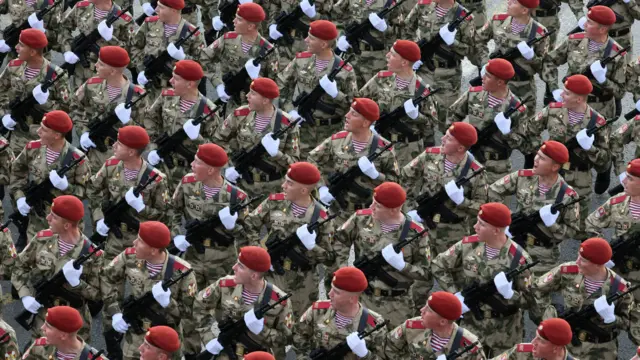 Soldiers in a line rehearsing, holding guns