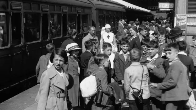 Black and white image of crowds of children on a rail platform
