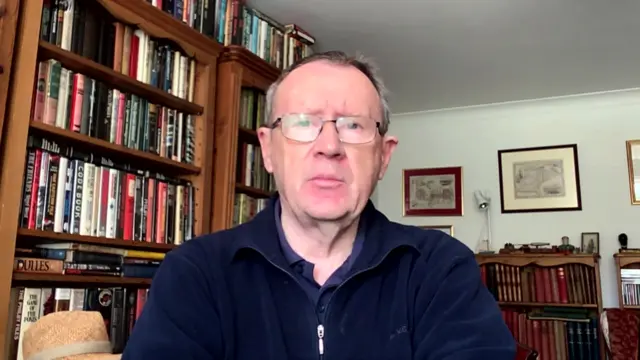 Tim Willasey-Wilsey seated in front of bookshelves