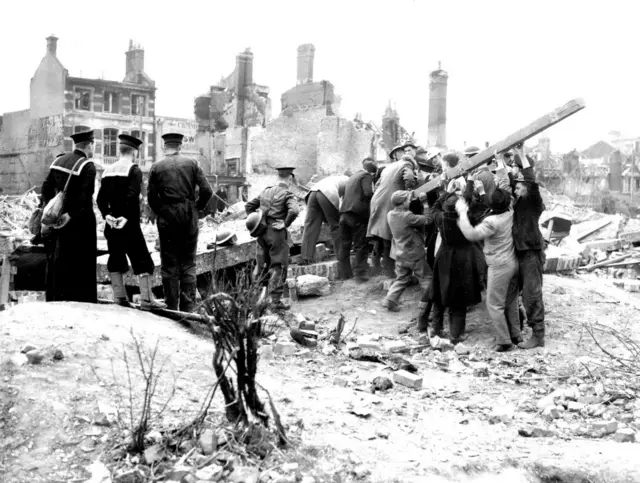 Black and white image of people digging through rubble after and air raid