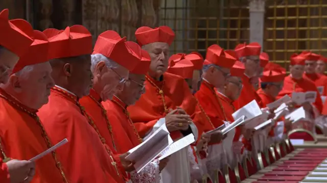 Cardinals, wearing red and white, in the Sistine Chapel