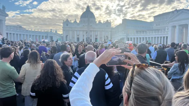 Spectators wait in St Peter's Square as the sun sets on Wednesday