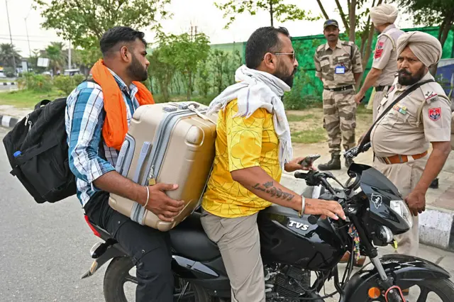 A policeman asks a passenger (L) to return after domestic and international flights were being cancelled at the Shri Guru Ram Das Ji International Airport on the outskirts of Amritsar on May 7, 2025, as border tensions surge.