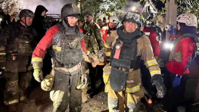 First responders carry a man out of the rubble of a building