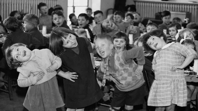 Black and white photo of a group of young children playing happily for the camera