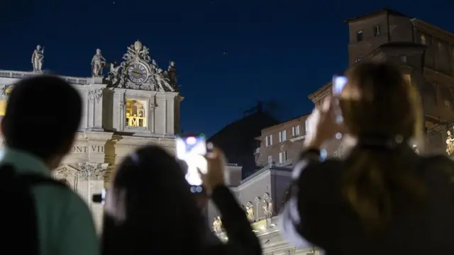 Faithful gathered in St. Peter's Square use their mobile phones as black smoke comes out of the chimney atop the Sistine Chapel