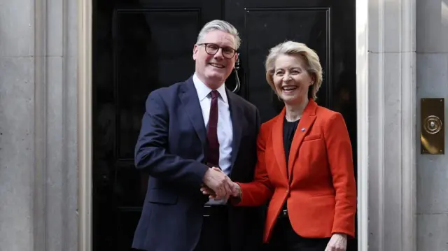 British Prime Minister Keir Starmer (L) welcomes President of the European Commission Ursula von der Leyen (R) to 10 Downing Street in London. They shake hands and smile and are both wearing blazers.