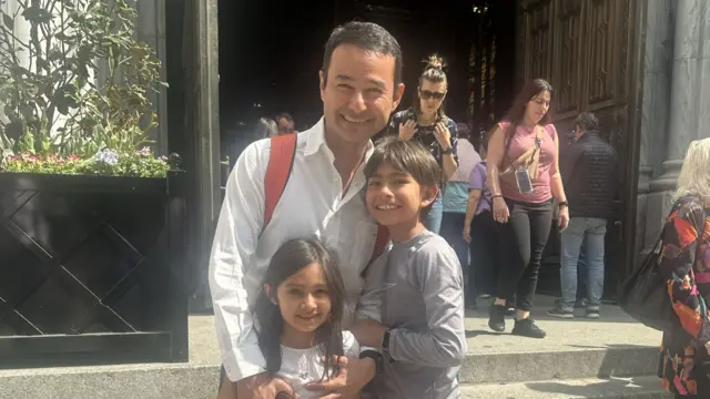 Fernando Aguilar smiles and holds his two children close.