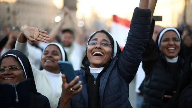 A nun holds up her hand in celebration while holding her phone