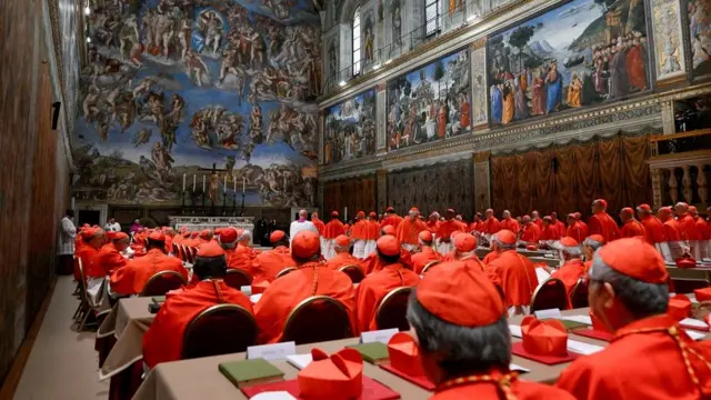 Cardinals wearing red face the altar at the Sistine Chapel