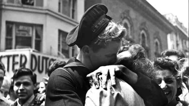 A man and a woman embrace as they kiss to celebrate the end of the war
