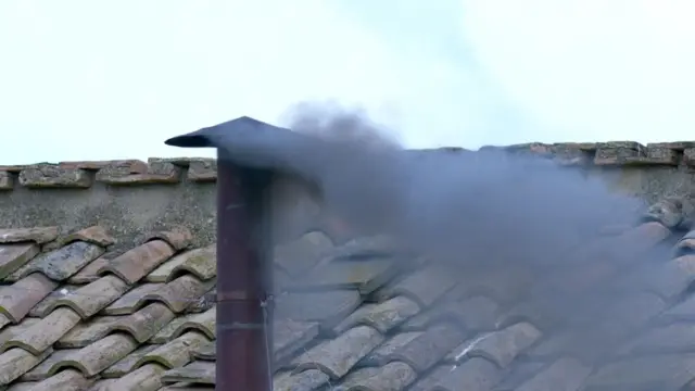 Black smoke coming from a chimney on the roof of the Sistine Chapel
