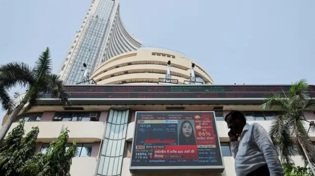 A man walks past a screen displaying market results outside the Bombay Stock Exchange (BSE) in Mumbai, India, April 7, 2025. REUTERS/Francis Mascarenhas