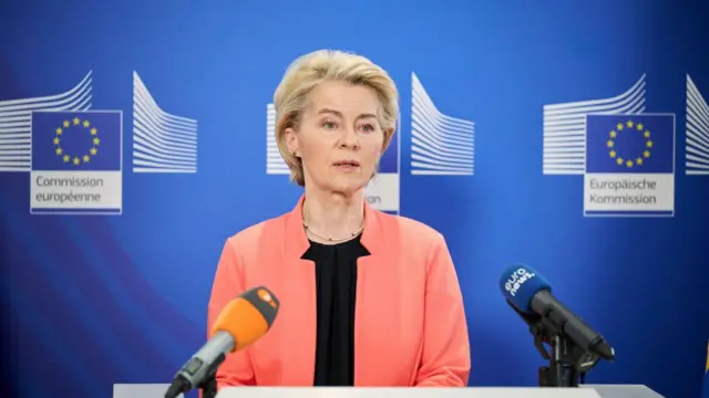 Ursula von der Leyen wears a pink blazer and black top during a press conference.