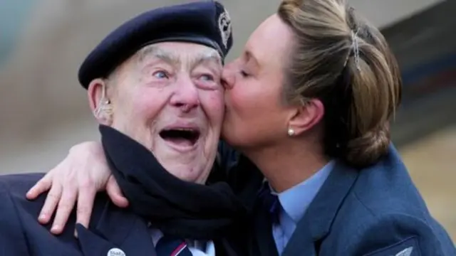 A veteran being kissed on the cheek by a woman
