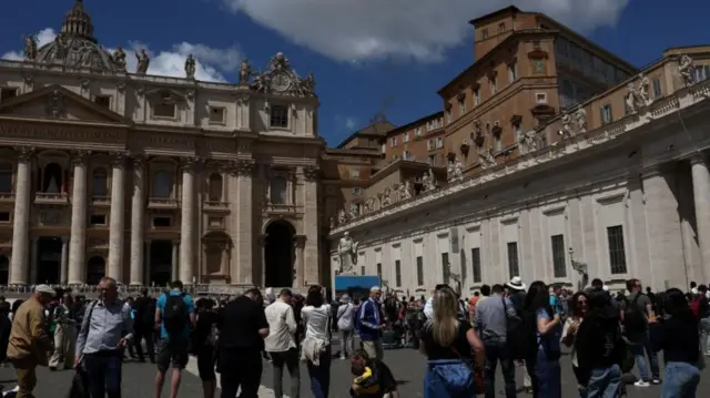 People watch as black smoke rises from the chimney on the Sistine Chapel