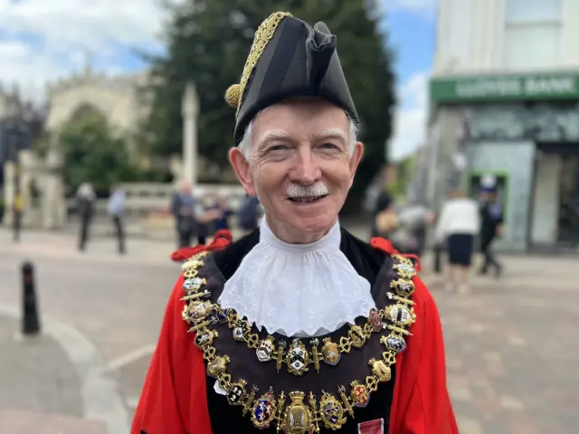 Andy Moore dressed in mayoral clothes, including a red jacket and chain, in Newbury town centre.
