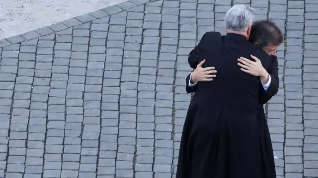 Two priests hug