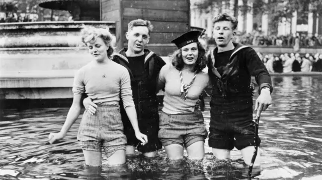 Two young women and two young men standing knee-deep in Trafalgar Square during VE Day celebrations on 8 May 1845