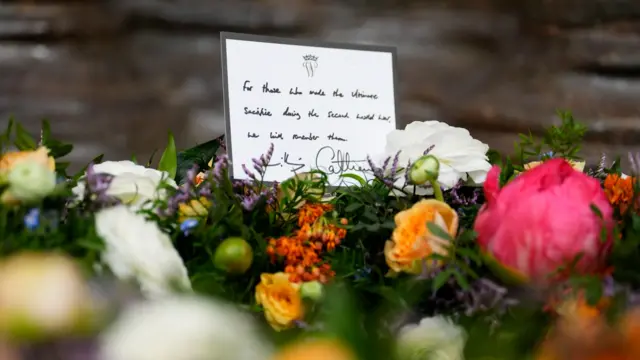 A handwritten note reads 'for those who made the ultimate sacrifice during the second world war, we will remember them', signed by Will and Kate, stands on a bed of colourful flowers.