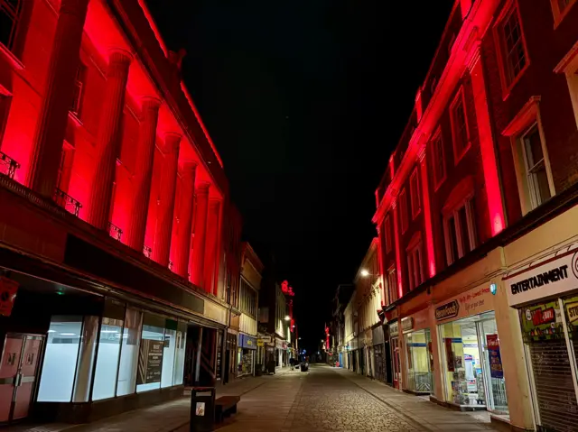 The shopping street of Whitefriargate in Hull with the tops of each building lit up red as part of the VE Day 80 celebrations.