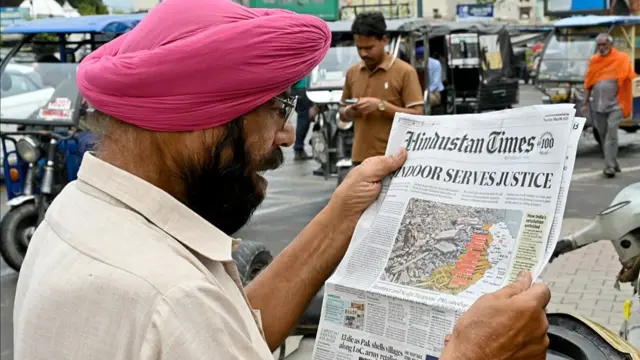 A man reads a newspaper with the front page article on the India-Pakistan conflict, a day after India launched strikes on Pakistan