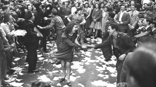 Young women and men dance in the streets of London.