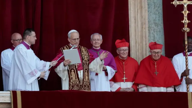 The pope stands on the balcony and speaks into a microphone