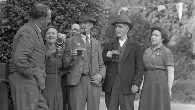 A group of people hold drinks on VE Day