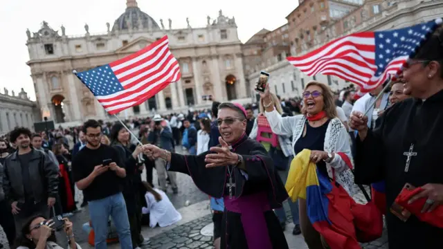 A bishop dances with a U.S. flag, after the announcement that U.S. Cardinal Robert Prevost has been elected by the conclave as new pope, with the name Pope Leo XIV, at the Vatican