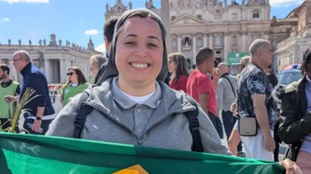 Sister Mona Lisa holding a Brazilian flag and smiling