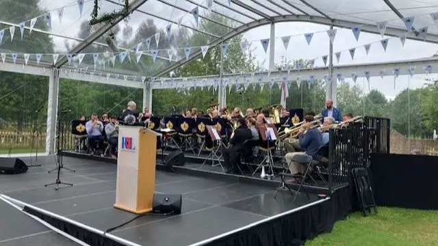 Military band practices on black stage at National Memorial Arboretum