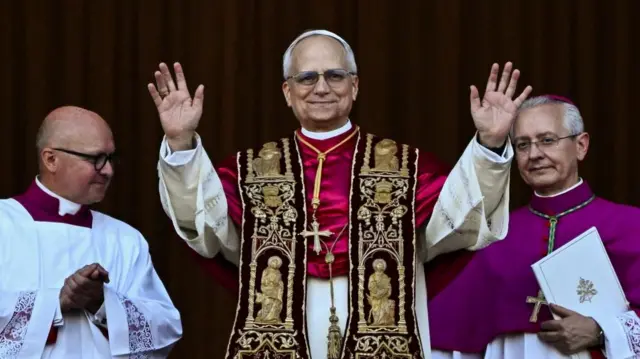 The new pope, standing on the balcony with his hands raised
