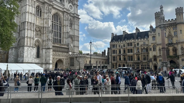 Crowds file out if Westminster Abbey with buildings in background