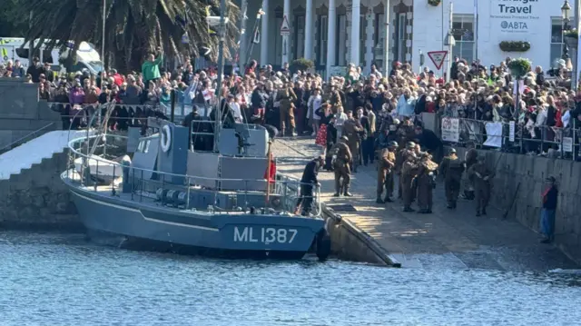 A boat against the slipway in the Victoria Marina in St Peter Port while a crowd watches on