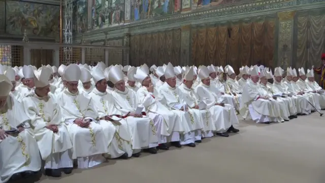 Inside the Sistine chapel, cardinals are in white robes and hats