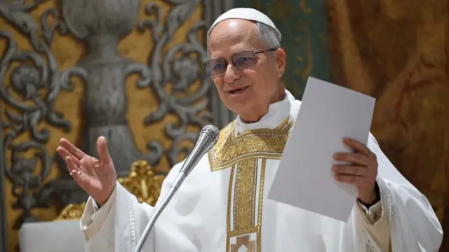 Pope Leo speaking into a microphone and holding a sheet of paper