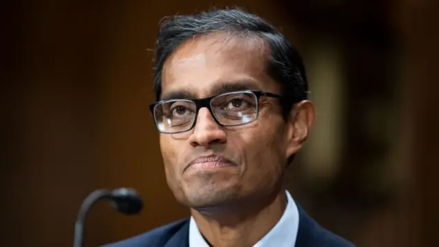 Judge Arun Subramanian in a blue suit, patterned tie and white shirt sits in front of a microphone.