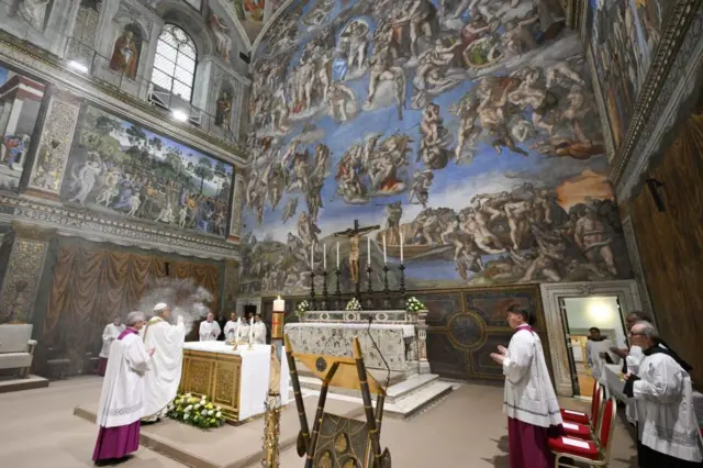 Pope Leo inside the Sistine Chapel, standing in front of the alter holding an incense burner