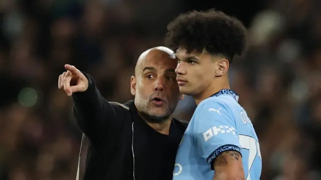 Manchester City boss Pep Guardiola speaking to Nico O'Reilly