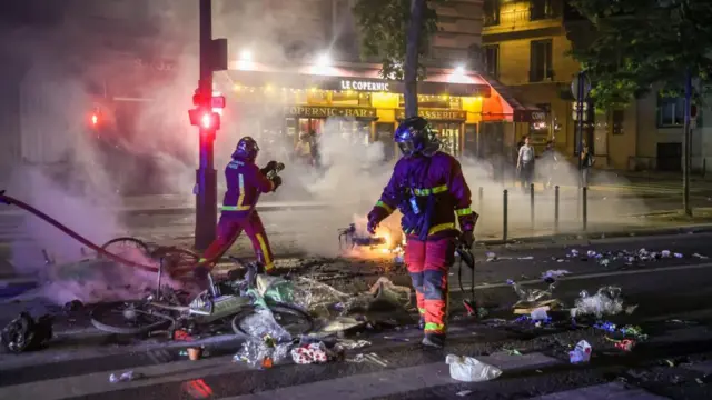 Firefighters with a hose on a street full of debris