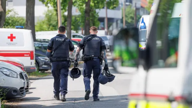 Police walking past some emergency vehicles