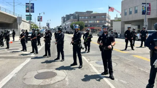 A line of police line up on a road which appears to be closed