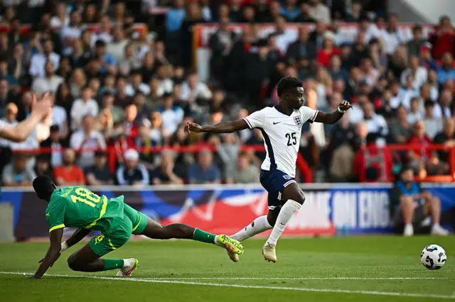 Senegal's midfielder#18 Ismaila Sarr (L) fights for the ball with England's midfielder #25 Bukayo Saka