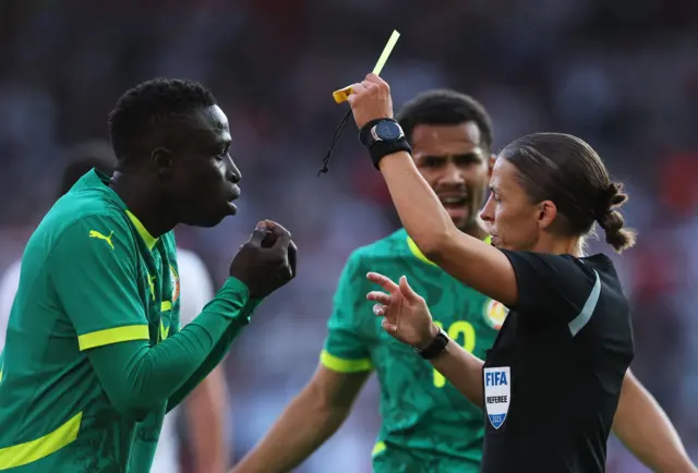 Senegal's Krepin Diatta is shown a yellow card by referee Stephanie Frappart